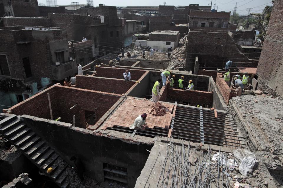 In this Thursday, March 14, 2013 photo, Pakistani workers rebuild homes which were damaged by an angry Muslim mob, in a Christian neighborhood, in Lahore. Pakistan’s blasphemy law has become a potent weapon in the arsenal of Muslim extremists, who use it against adherents of minority religions. (AP Photo/Nathalie Bardou)