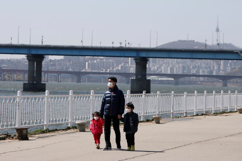 A man and children wearing masks to protect against contracting the coronavirus disease (COVID-19) take a walk at a Han River Park in Seoul