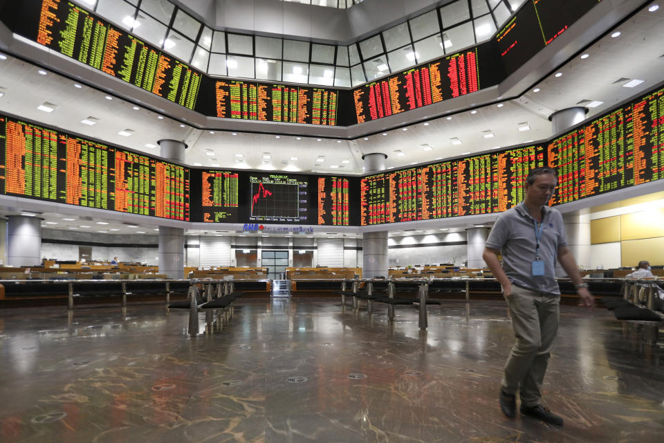 Visitor walk under a stock trading board at a private stock market gallery in Kuala Lumpur, Malaysia, Friday, Jan. 11, 2019. Asian markets were mostly higher on Friday as investors cheered a more reactive Federal Reserve and U.S.-China trade talks.(AP Photo/Vincent Thian)