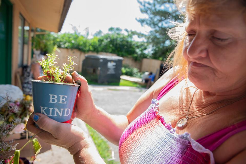 Karen Delaney holds one of the many plants she keeps outside her room at Motels4Now in South Bend on Friday, July 14, 2023.