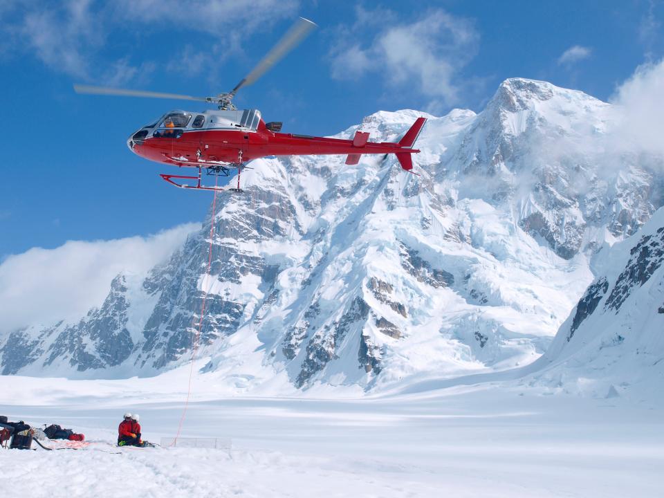 Helicopter hovers in Denali National Park with Mt. Hunter in the background.