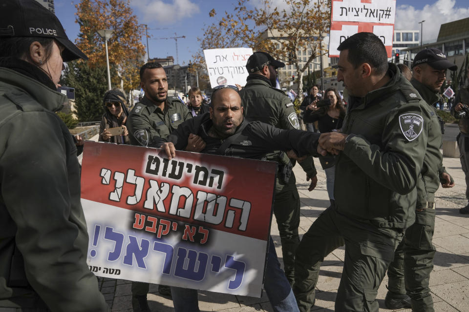 FILE - Israeli border police officers move a right wing protester from a left wing protest against the appointment of Aryeh Deri the leader of the ultra-Orthodox Shas party as the country's new health minister, in front of the Supreme Court in Jerusalem, Thursday, Jan, 5, 2023. Deri pleaded guilty to tax fraud last year and previously served time in prison for accepting bribes. Hebrew on sight reads, ״The leftist minority will not decide for Israel". (AP Photo/Mahmoud Illean, File)