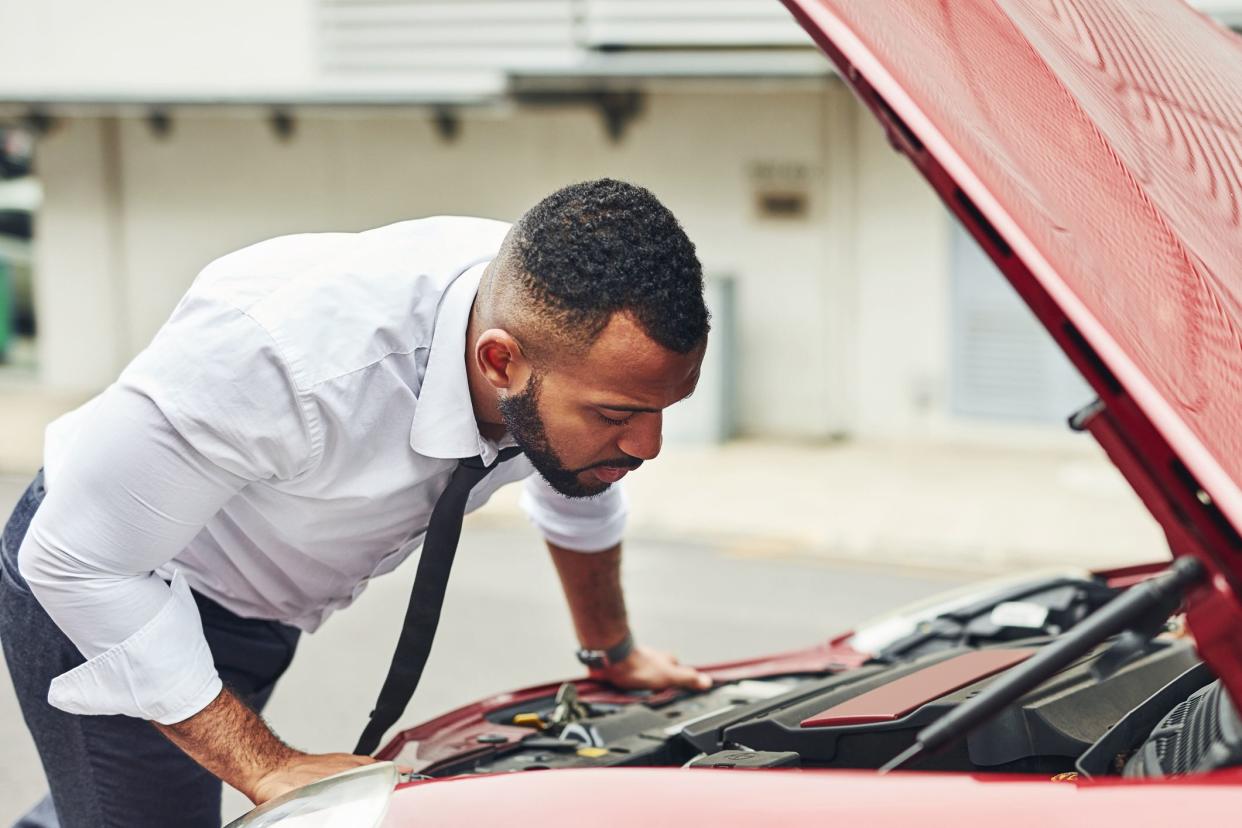 Shot of a man checking under the hood of his car after breaking down