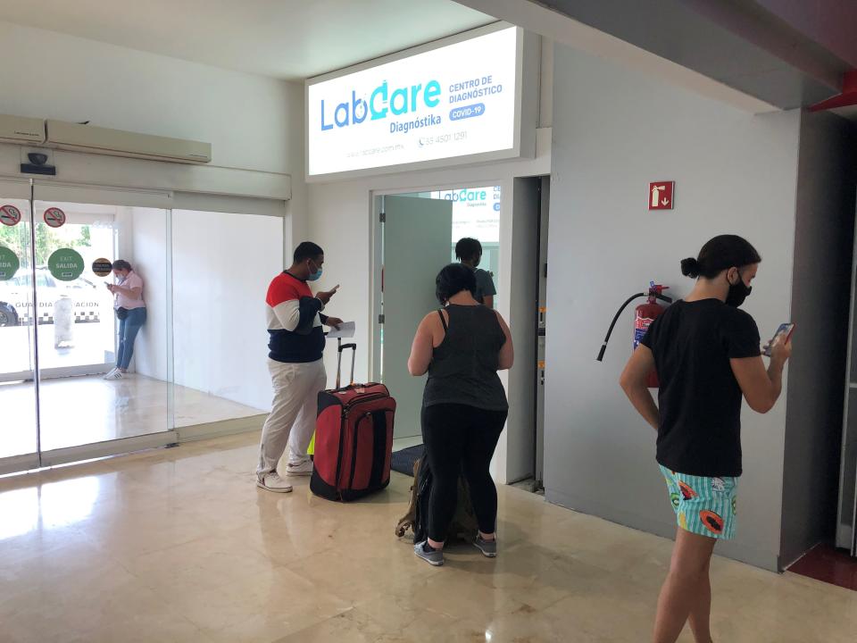 Travelers wait in line for a COVID test at Cancun International Airport.