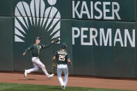 Oakland Athletics center fielder Mark Canha, left, cannot catch a two-run double hit by Houston Astros' Yuli Gurriel during the third inning of a baseball game in Oakland, Calif., Sunday, April 4, 2021. Also pictured is Athletics right fielder Stephen Piscotty (25). (AP Photo/Jeff Chiu)