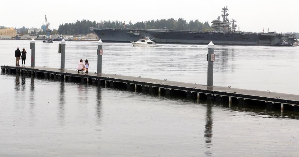 People watch the USS Nimitz head for the pier at Naval Base Kitsap from the dock of the Port Orchard Boat Launch on Sunday, Sept. 24, 2023.