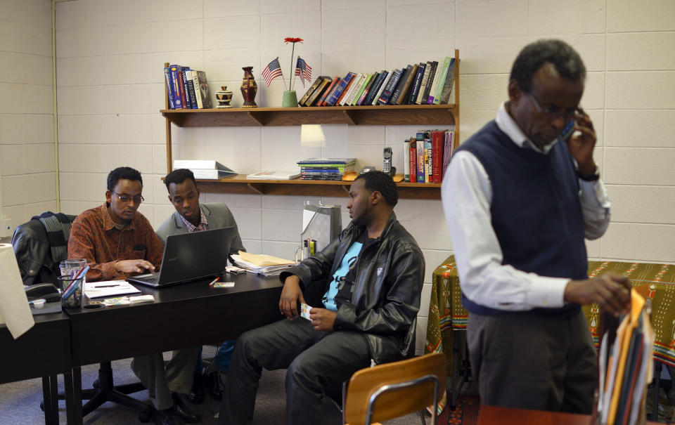 Ibrahim Hassan, left, a navigator at the Somali Health Solutions office, wraps up MNsure health insurance marketplace enrollment for Ahmed Ali of Hopkins, while another client waits his turn, Monday, March 31, 2014, in Minneapolis. The call center for Minnesota's online health insurance marketplace strained Monday under a crush of people trying to beat the midnight Monday deadline for open enrollment, while residents lined up to take advantage of locations offering in-person help. (AP Photo/Star Tribune, Jeff Wheeler)