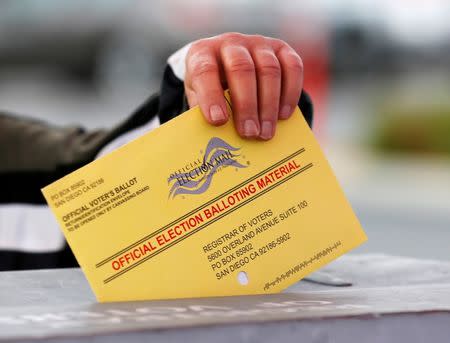 FILE PHOTO: A poll worker places a mail in ballot into a voting box as voters drop off their ballot in the U.S. presidential primary election in San Diego, California, United States June 7, 2016. REUTERS/Mike Blake/File Photo