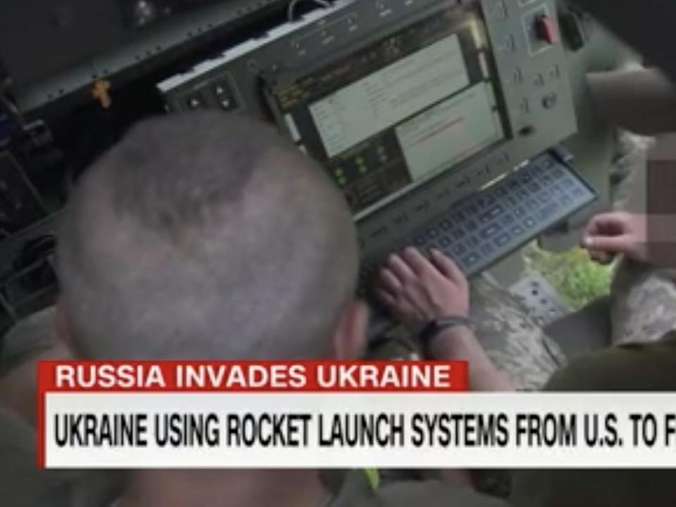 A still from CNN footage showing two Ukrainian soldiers inside a HIMARS truck, showing them operating its system