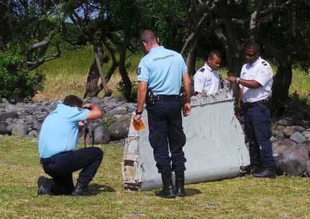 French gendarmes and police inspect a large piece of plane debris which was found on the beach in Saint-Andre, on the French Indian Ocean island of La Reunion, July 29, 2015. REUTERS/Zinfos974/Prisca Bigot