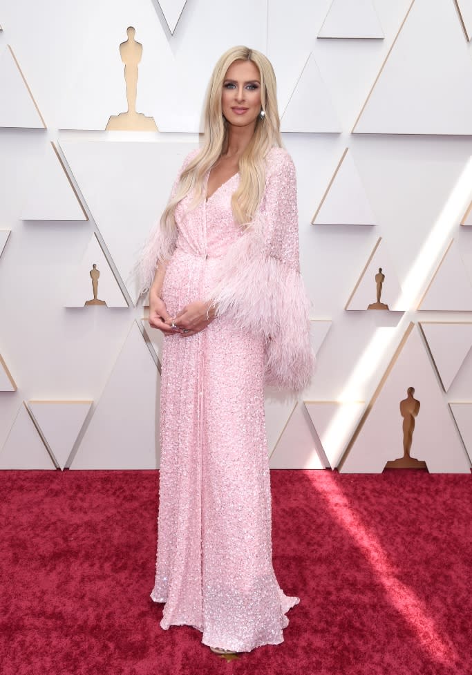 Nicky Hilton hits the red carpet in a pink sequined gown featuring a feather-embellished cape at the Oscars on March 27, 2022. - Credit: Gilbert Flores for Variety