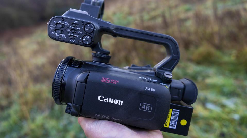 The Canon XA65 camcorder being held in a female hand at sunrise