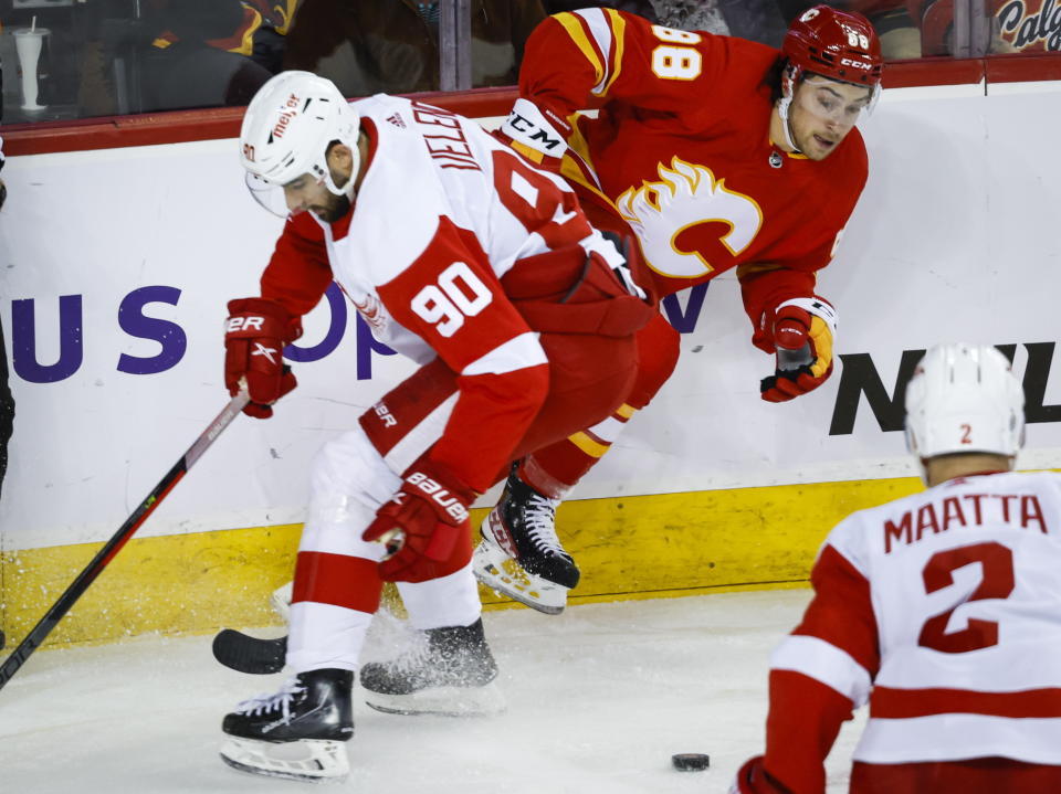 Detroit Red Wings forward Joe Veleno, left, checks Calgary Flames forward Andrew Mangiapane during first-period NHL hockey game action in Calgary, Alberta, Thursday, Feb. 16, 2023. (Jeff McIntosh/The Canadian Press via AP)