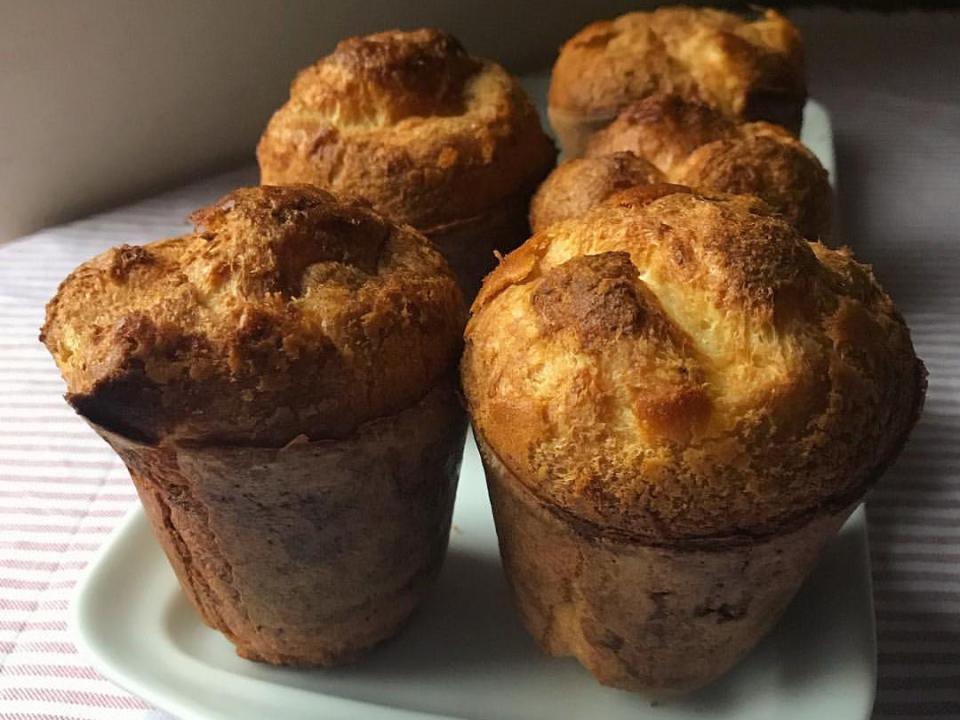 Golden-brown popovers lined up on white tray