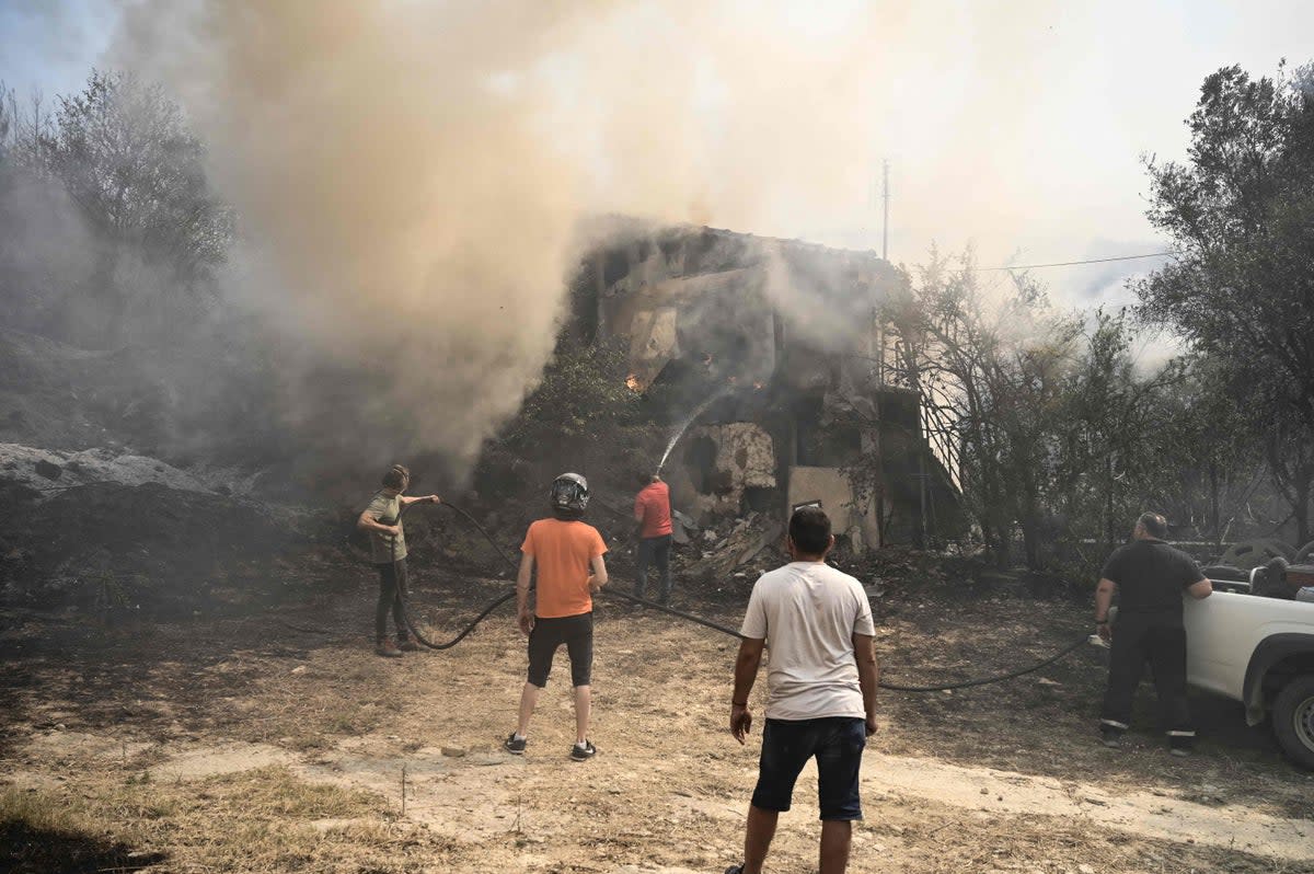 Local residents seen extinguishing a fire in Avanta as smoke covers the air (AFP via Getty Images)