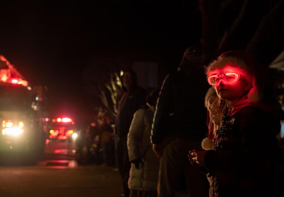 A kid wearing red neon glasses watches the floats drive in front of him during the annual Holiday Parade of Lights in Pacific Grove, Calif., on Thursday Dec. 2, 2021. 