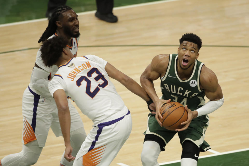 Milwaukee Bucks' Giannis Antetokounmpo (34) looks to shoot past Phoenix Suns' Cameron Johnson (23) and Jae Crowder during the second half of Game 3 of basketball's NBA Finals, Sunday, July 11, 2021, in Milwaukee. (AP Photo/Aaron Gash)