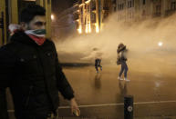 Anti-government protesters are sprayed by a water canon, during ongoing protests against the political elites who have ruled the country for decades, in Beirut, Lebanon, Sunday, Jan. 19, 2020. Lebanese security forces used tear gas, water cannons and rubber bullets in clashes with hundreds of anti-government protesters outside the country's Parliament on Sunday, as violence continued to escalate in a week of rioting in the capital. (AP Photo/Hassan Ammar)