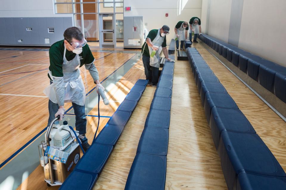 Austin O'Malley, along with the custodial team, sterilizes gymnasium seats as they make their way though South West Middle School in Quincy. Cleaning public spaces across the city has contributed to $6.5 million in city spending in response to the coronavirus.
