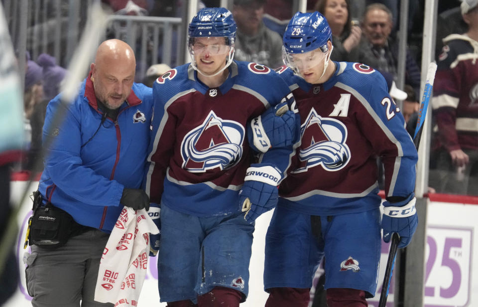 Colorado Avalanche left wing Artturi Lehkonen, center, is helped to the team box by trainer Matt Sokolowski, left, and center Nathan MacKinnon after being injured in the second period of an NHL hockey game against the Seattle Kraken on Thursday, Nov. 9, 2023, in Denver. (AP Photo/David Zalubowski)