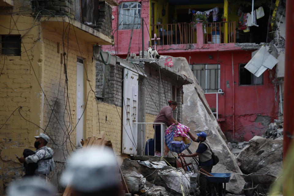 Residents evacuate from their home at the site of a landslide that brought tons of massive boulders down on a steep hillside neighborhood, in Tlalnepantla, on the outskirts of Mexico City, Saturday, Sept. 11, 2021. A section of the peak known as Chiquihuite gave way Friday afternoon, plunging rocks the size of small homes onto the densely populated neighborhood. (AP Photo/Ginnette Riquelme)