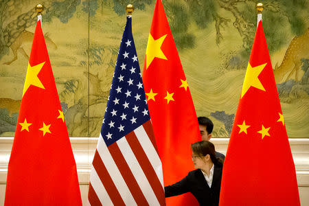 Chinese staffers adjust U.S. and Chinese flags before the opening session of trade negotiations between U.S. and Chinese trade representatives at the Diaoyutai State Guesthouse in Beijing, Thursday, Feb. 14, 2019. Mark Schiefelbein/Pool via REUTERS