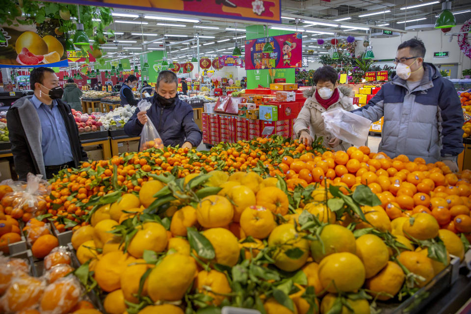 Varias personas compran cítricos en un supermercado de Beijing, protegidos por una mascarilla facial, en Beijing, China, el 28 de enero de 2020. (AP Foto/Mark Schiefelbein)