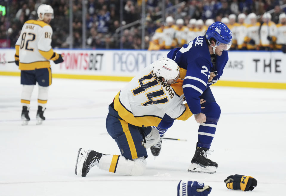 Nashville Predators forward Kiefer Sherwood (44) and Toronto Maple Leafs defenseman Jake McCabe (22) fight during third-period NHL hockey game action in Toronto, Saturday, Dec. 9, 2023. (Nathan Denette/The Canadian Press via AP)