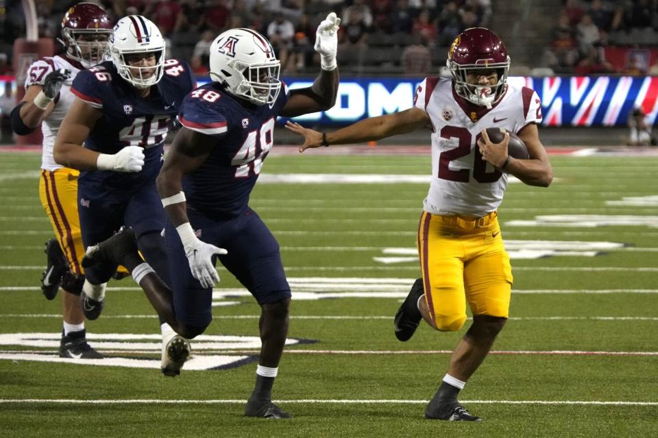 USC running back Travis Dye runs away from Arizona defensive lineman Ta'ita'i Uiagalelei and linebacker Jerry Roberts.