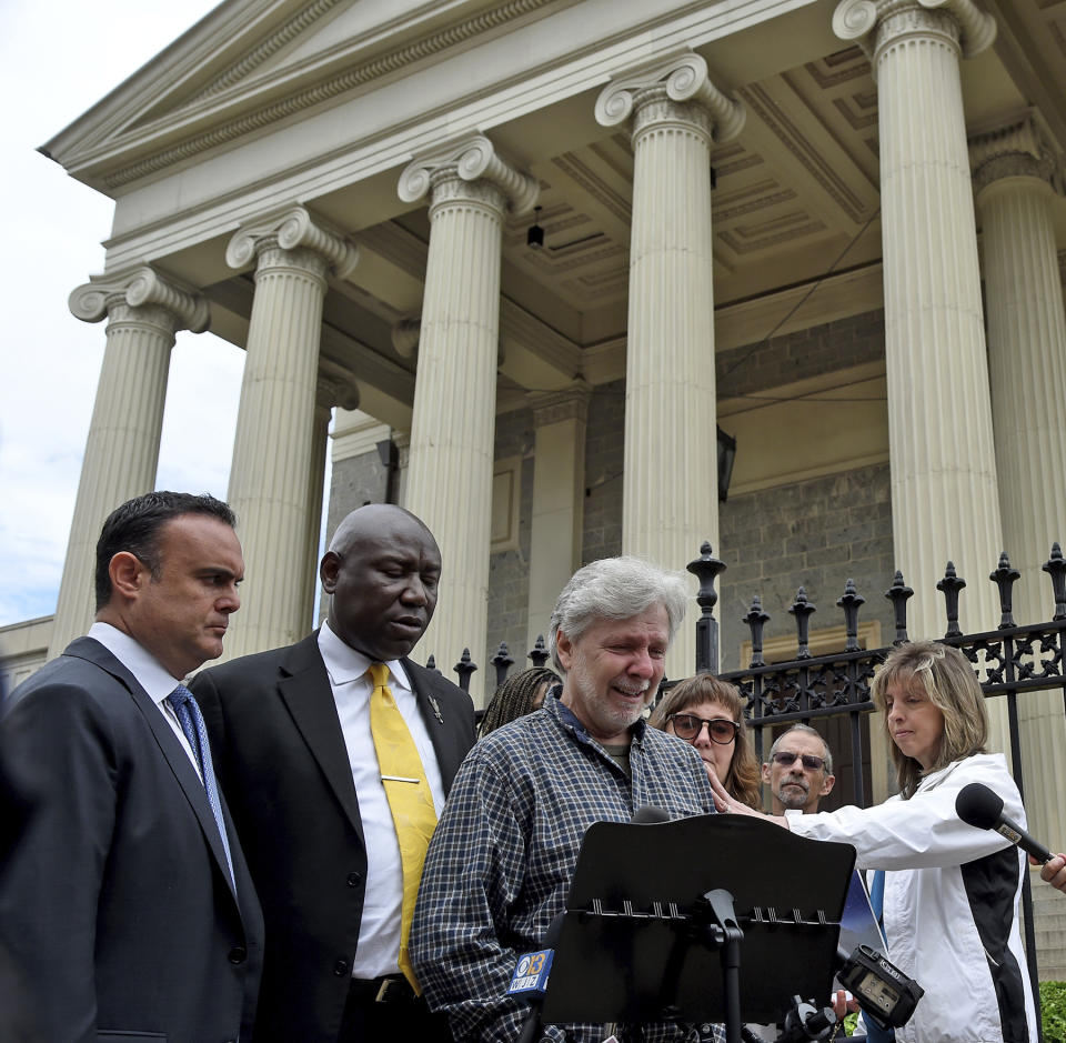 Clergy abuse victim Marc Floto, at podium, of Westminster is comforted by his wife Melissa, right, as he shares his experiences during a news conference with attorneys Adam Stater, left, and Ben Crump, Tuesday, May 9, 2023, in Baltimore. After Maryland lawmakers recently passed legislation eliminating the statute of limitations for child sex abuse lawsuits amid increased scrutiny of the Archdiocese of Baltimore, civil rights attorney Ben Crump announced a series of civil claims Tuesday he plans to bring on behalf of victims. (Barbara Haddock Taylor/The Baltimore Sun via AP)