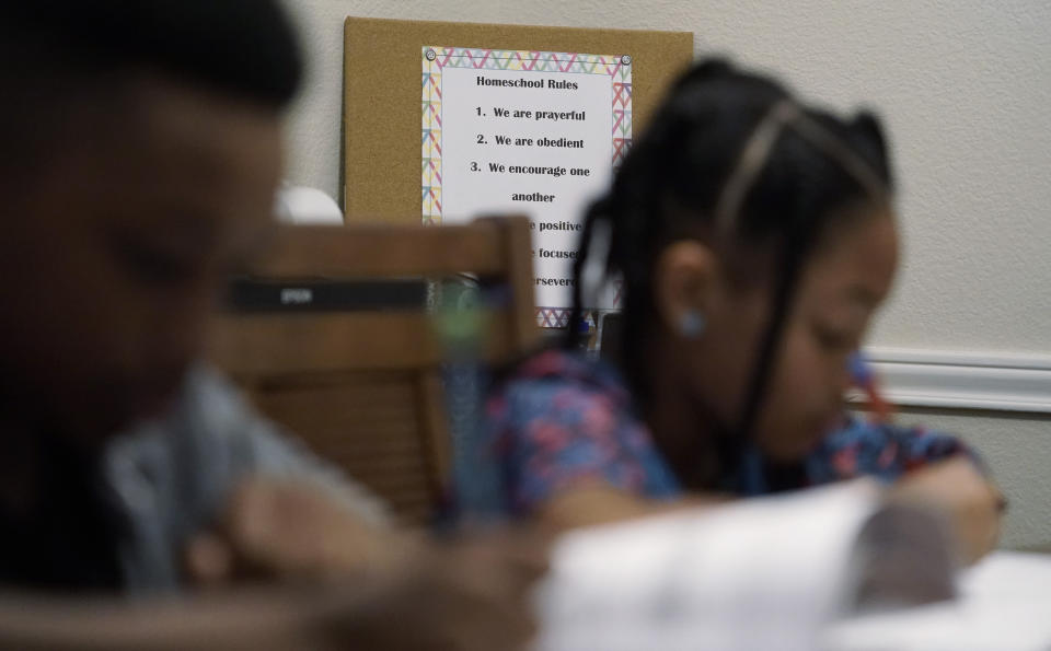 The family rules for homeschool are posted behind Jacoby Brown, 11, and sister Felicity, 9, as they practice math at home in Austin, Texas, Tuesday, July 13, 2021. “I didn’t want my kids to become a statistic and not meet their full potential,” said their father, Robert, a former teacher who now does consulting. “And we wanted them to have very solid understanding of their faith.” (AP Photo/Eric Gay)