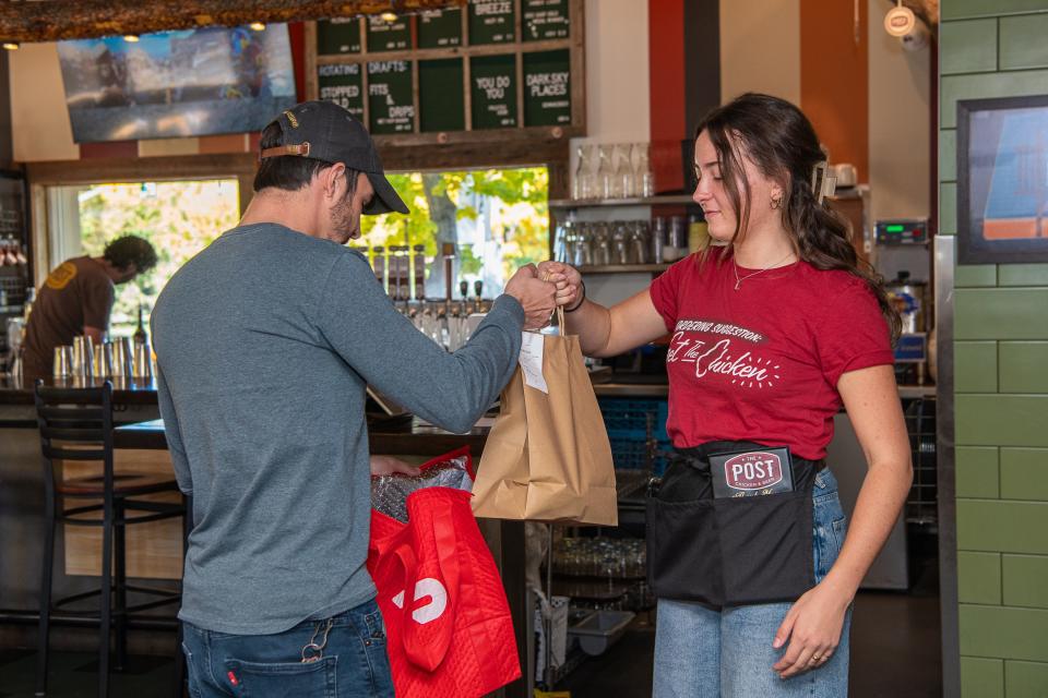 Lia Sukornyk gives Tom Harms a delivery order from the Tender Lovin' Mac Project, a ghost kitchen that operates out of The Post Chicken and Beer, on Oct. 19 in Fort Collins.