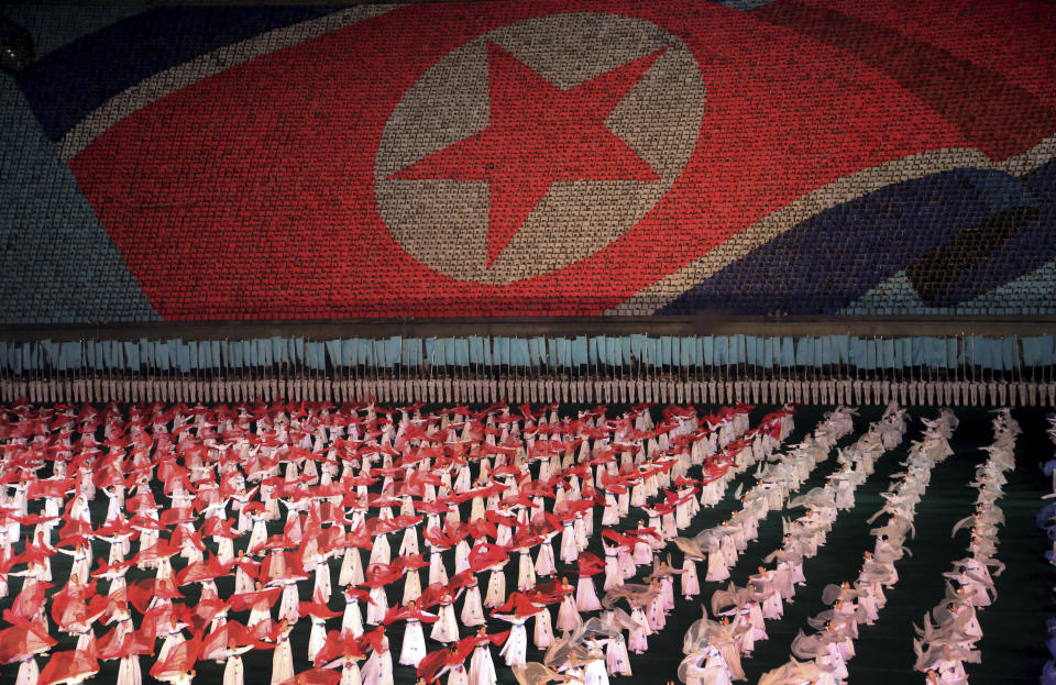 FILE - In this July 22, 2013, file photo, North Korean women dance in front of a display of their country's national flag in Pyongyang, North Korea. North Korea is bringing back one of its most iconic art forms - mass games performed by tens of thousands of people working in precise unison - to mark its 70th anniversary on Sunday, Sept. 9, 2018. The performance, which takes months if not years of intense preparation and training, is being called “Glorious Country” this year. (AP Photo/Wong Maye-E)