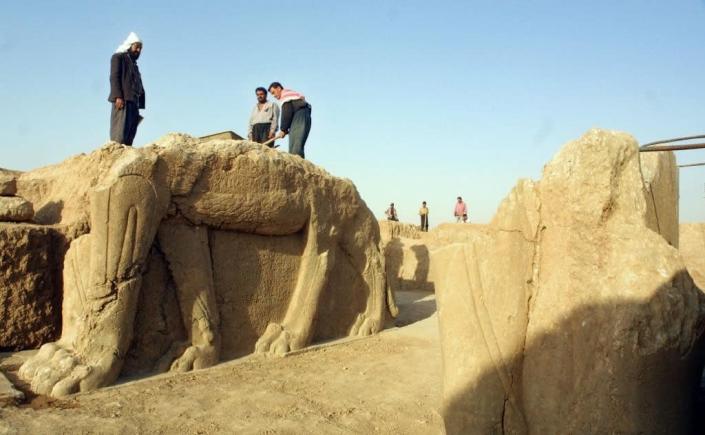 File photo shows Iraqi workers cleaning a statue of winged bull at an archeological site in Nimrud, southeast of Mosul (AFP Photo/Karim Sahib)