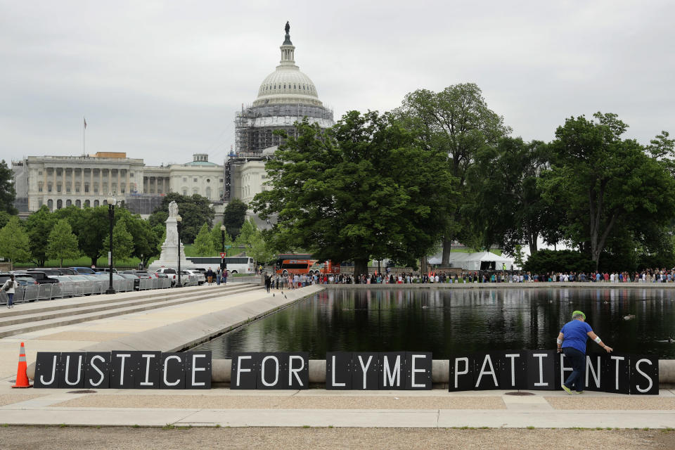 Bunny Woloszczak of Hurleyville, New York, places a protest sign near the U.S. Capitol Reflecting Pool as part of a "We The People Rally" to bring awareness about Lyme disease May 19, 2016, in Washington, D.C.