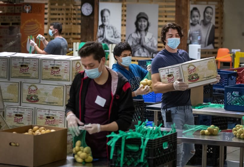 IRVINE, CA -- WEDNESDAY, APRIL 1, 2020: Jose Secundino, center in blue sweatshirt, joins fellow recently hired Second Harvest Food Bank of Orange County temporary employees, who have been laid off from restaurant jobs due to the coronavirus pandemic, as they pack boxes of food for the needy. Volunteers then picked up the food and delivered it to local senior centers in Orange County. Photo taken at Second Harvest Food Bank at the Orange County Great Park in Irvine, CA, on April 1, 2020. (Allen J. Schaben / Los Angeles Times)