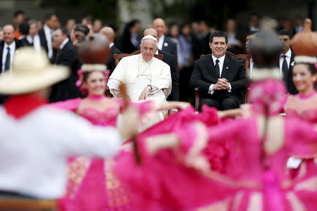 Pope Francis (L) watch a dance performance next to Paraguay's President Horacio Cartes upon his arrival at the international airport in Asuncion, Paraguay, July 10, 2015. REUTERS/Andres Stapff