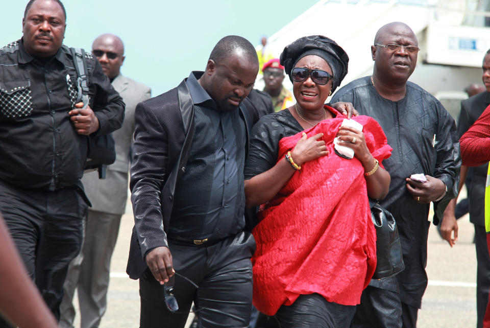 Unidentified family members mourn as they arrive from Kenya accompanying the flag draped coffin of celebrated poet, professor, and ambassador Kofi Awoonor, at the airport in Accra, Ghana, Wednesday, Sept. 25, 2013. Mourners sang funeral dirges and traditional leaders poured libations Wednesday for the beloved literary icon, as hundreds gathered at the airport where his body was brought home days after he was slain in the Kenya mall terror attack. Awoonor had been in Kenya with his son to take part in a literary festival, when he was among the more than 60 civilians killed at the Nairobi mall.(AP Photo/Christian Thompson)