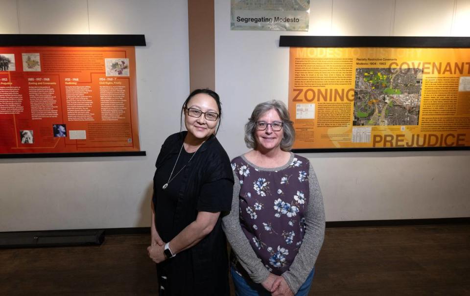 History professors Eva Mo, left, and Eileen Kerr stand with a display in Founder’s Hall of research conducted by students that shows Modesto’s history of segregation, the lost Chinatown, & Dust Bowl refugees in the Airport District.