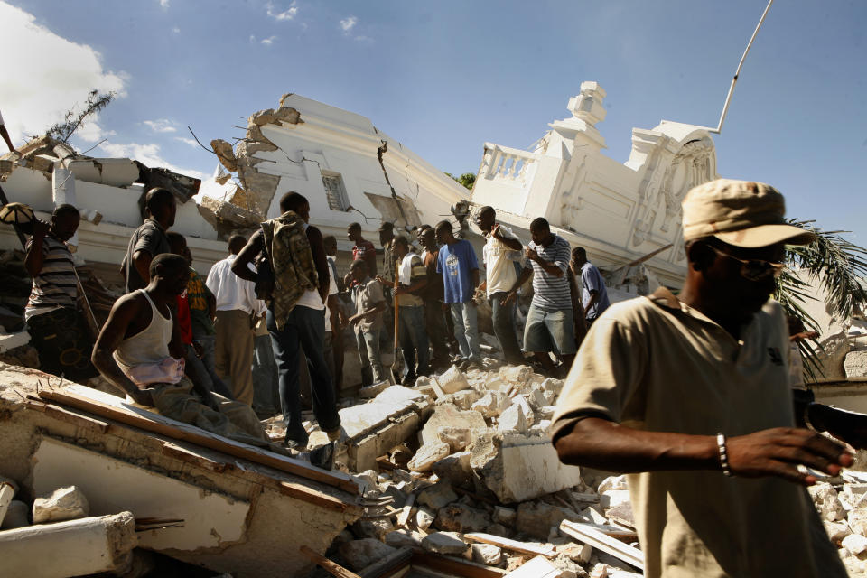 <p>The Department of Justice was flattened by the earthquake. Men gather to try to get to those still buried in the rubble without any assistance in Port-au-Prince, Haiti, Jan.13, 2010. (Photo: Carolyn Cole/Los Angeles Times via Getty Images) </p>