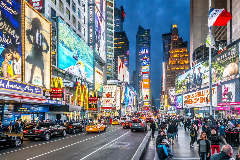 Times Square bustling with traffic and illuminated with electronic billboards