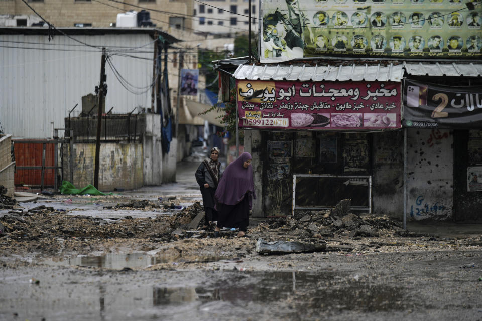 People walk by a destroyed road following an Israeli army operation in Jenin refugee camp, West Bank, Sunday, Nov. 19, 2023. (AP Photo/Majdi Mohammed)