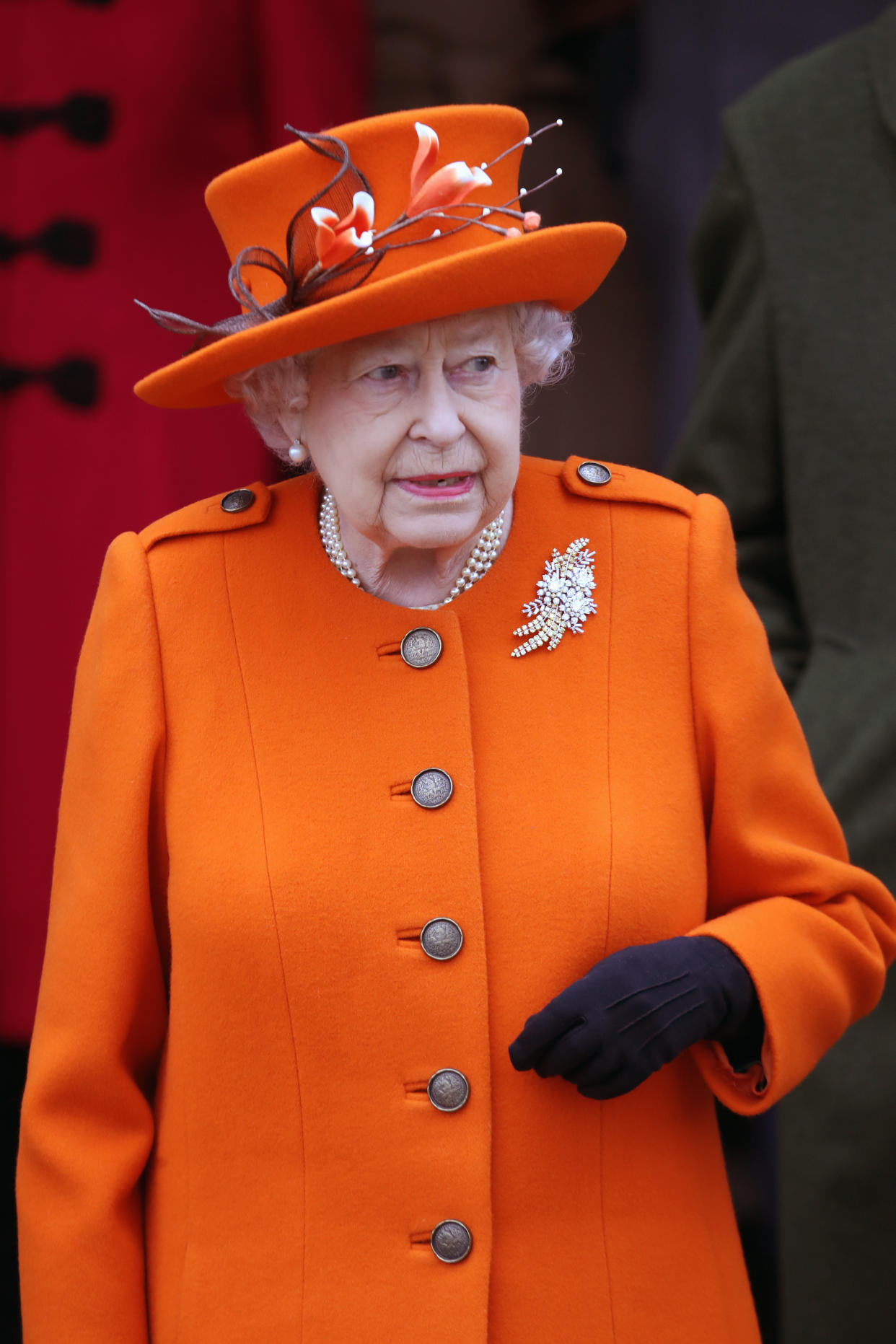 The Queen wears orange hat and coat