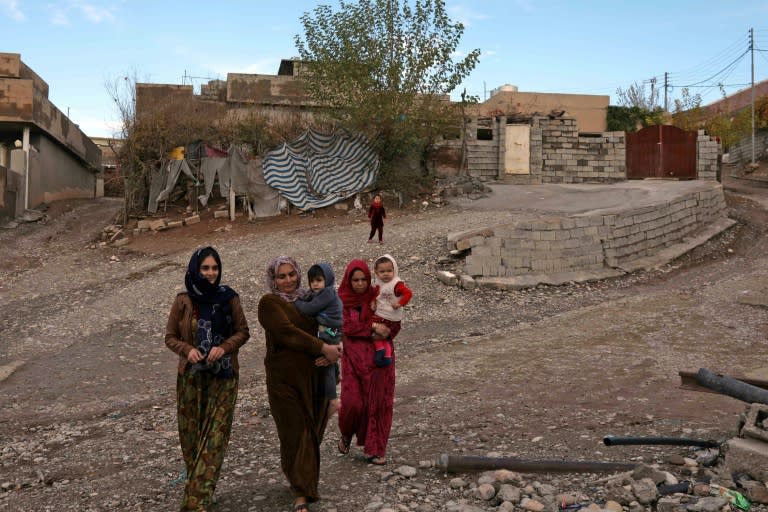 Women carry children through the Iraqi Kurdish village of Sharboty Saghira on December 3, 2018