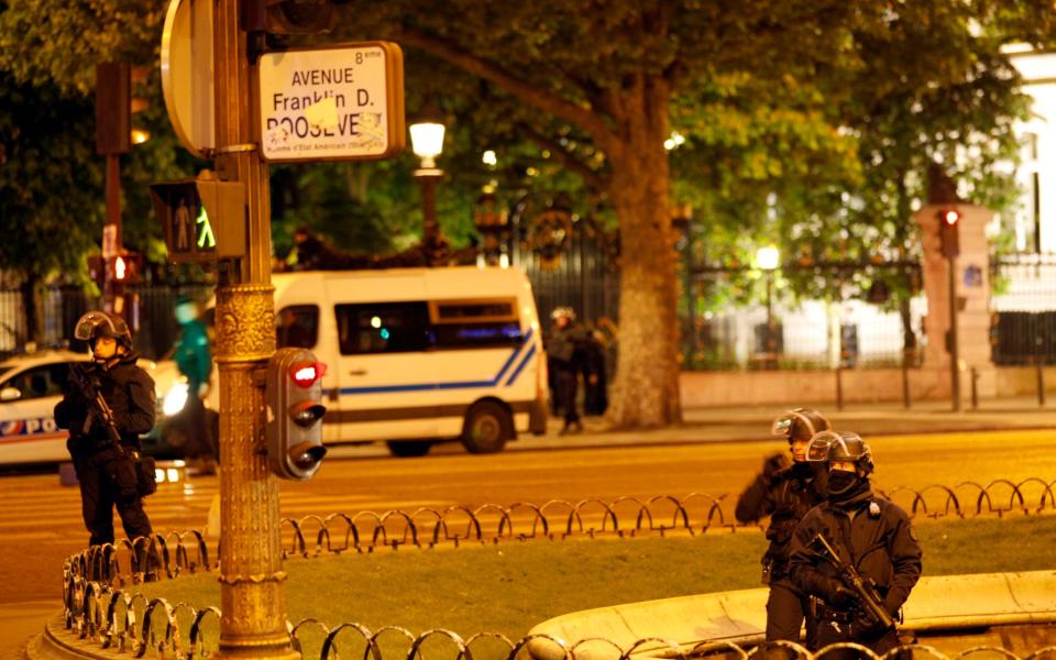 Police officers take positions near the Champs Elysees avenue in Paris, France, after a fatal shooting in which a police officer was killed along with an attacker - Credit: AP