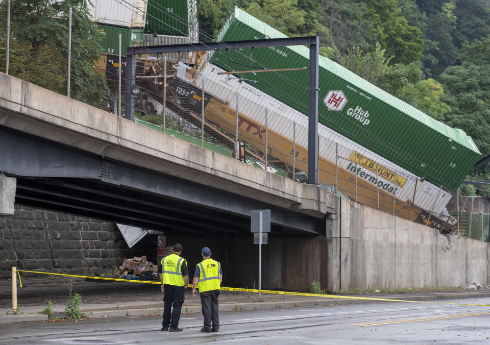 Emergency personnel work the scene of a train derailment above Carson Street on Sunday, Aug. 5, 2018, near Station Square in Pittsburgh. Four cars from a freight train derailed in Pittsburgh, sending containers tumbling down a hillside onto light rail tracks below, but no injuries have been reported, authorities said. (Steph Chambers/Pittsburgh Post-Gazette via AP)