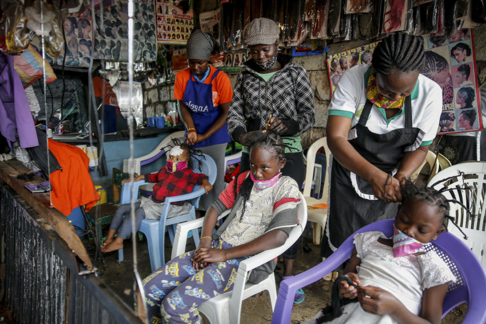 FILE - In this Sunday, May 3, 2020 file photo, Gettrueth Ambio, 12, center, Jane Mbone, 7, right, and Hamida Bashir, 3, left, have their hair styled in the shape of the new coronavirus, at the Mama Brayo Beauty Salon in the Kibera slum, or informal settlement, of Nairobi, Kenya. The coronavirus has revived a hairstyle in East Africa, one with braided spikes that echo the virus' distinctive shape, with the growing popularity in part due to economic hardships linked to virus restrictions. (AP Photo/Brian Inganga, File)