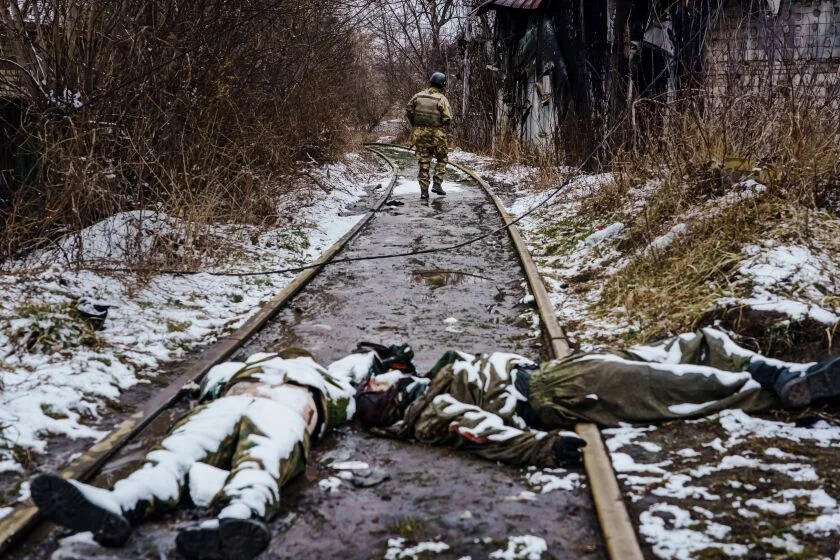 IRPIN, UKRAINE -- 2022년 3월 1일: 우크라이나 군인이 2022년 3월 1일 화요일 우크라이나 이르핀 외곽에서 러시아군과 전투가 벌어졌던 죽은 러시아 군인의 시신을 지나 무언가를 조사하기 위해 철도를 따라 방황하고 있습니다. (마커스 얌 / LOS ANGELES TIMES)