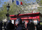 A man waves the French flag as he sits atop a venders cabin at the Place de Republique during a yellow vest demonstration in Paris, Saturday, April 20, 2019. French yellow vest protesters are marching anew to remind the government that rebuilding the fire-ravaged Notre Dame Cathedral isn't the only problem the nation needs to solve. (AP Photo/Michel Euler)