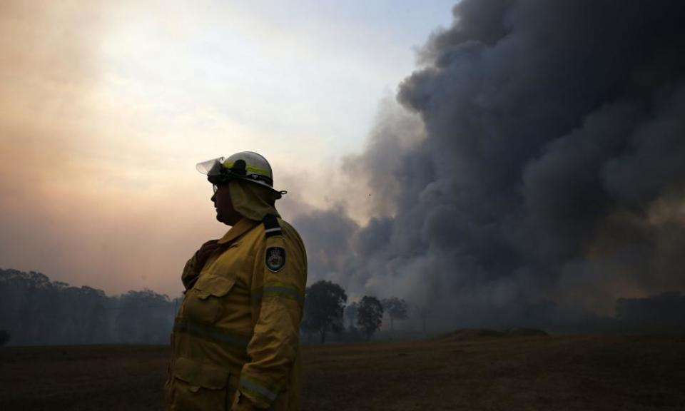 A firefighter talks on a radio as an out of control fire burns at Avery’s lane, near Stanford Merthyr, east of Cessnock on Tuesday.